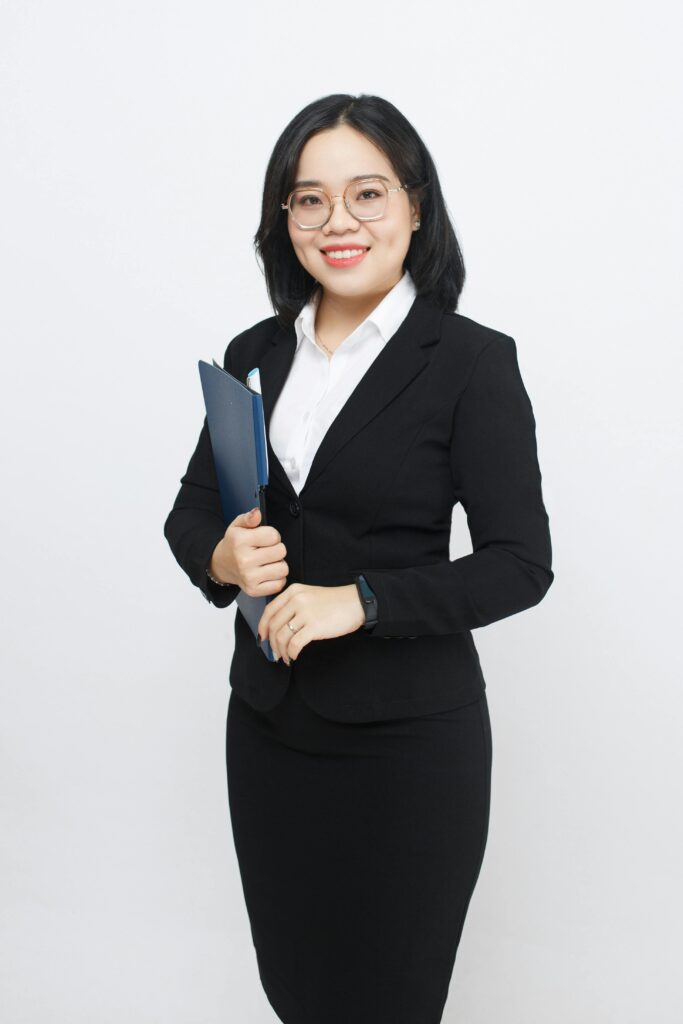 Confident businesswoman smiling in a studio setting, holding documents in a modern fashion.
