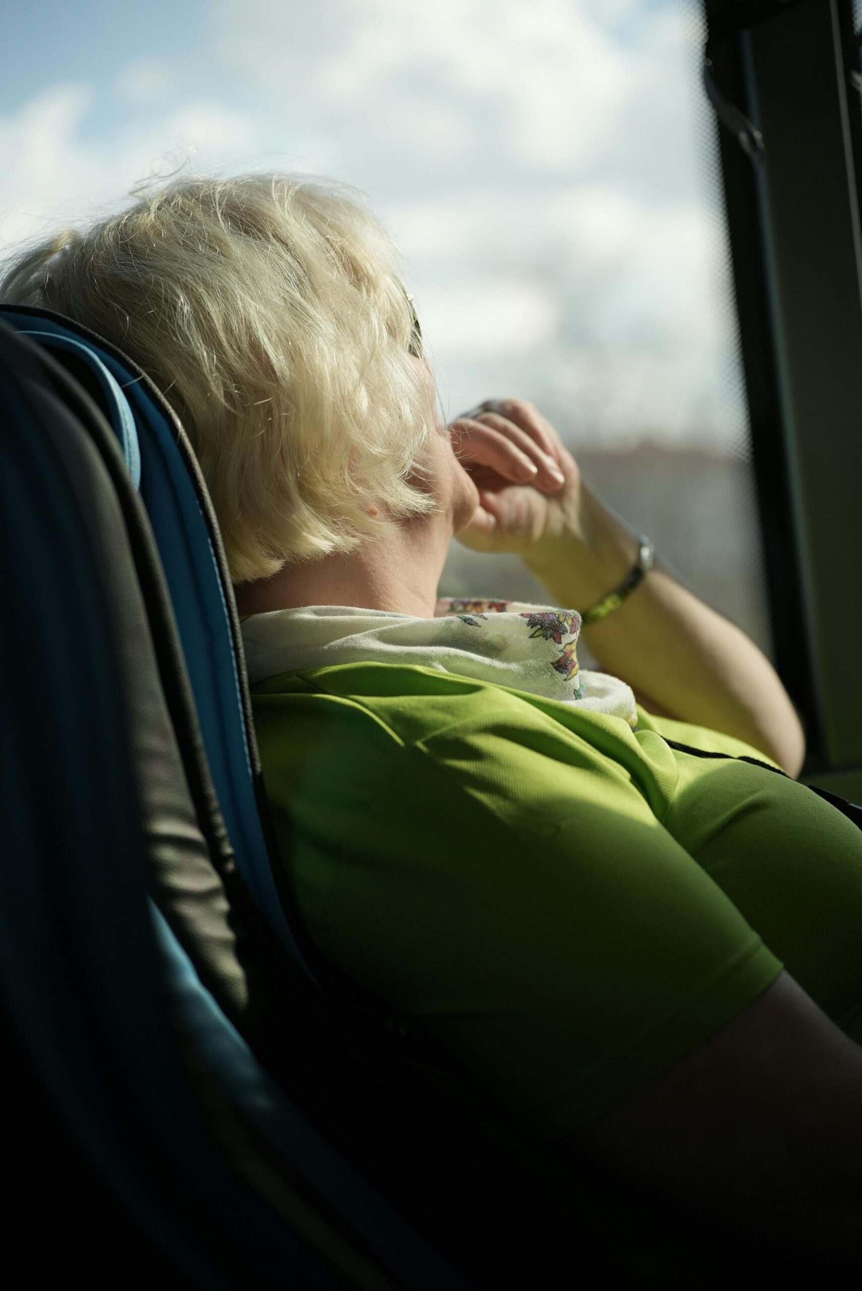 Senior woman enjoying a scenic bus ride, gazing out the window with a relaxed demeanor.