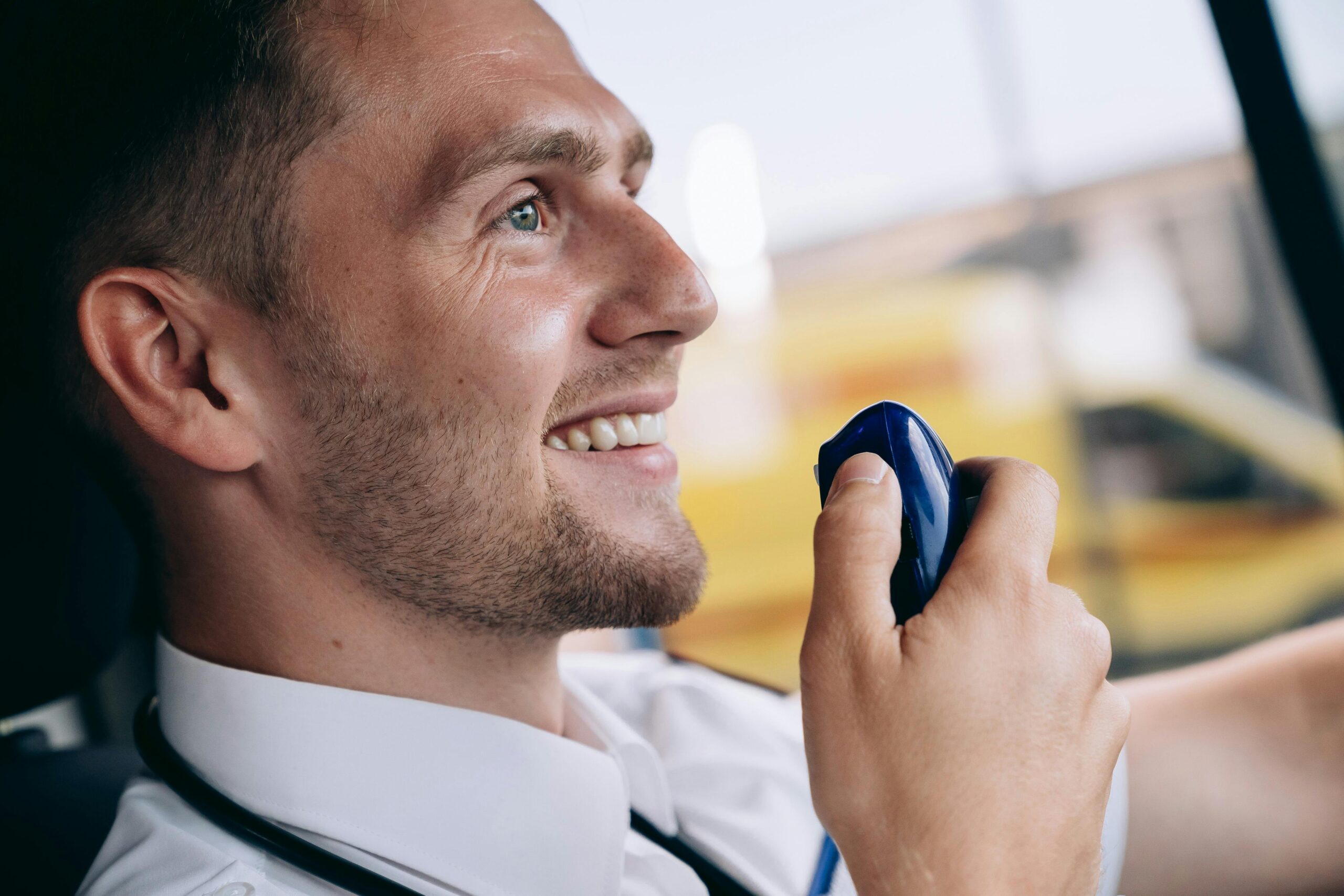 Friendly paramedic communicating via radio inside emergency vehicle. Professional healthcare setting.